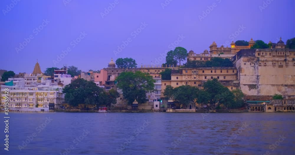 Udaipur City at sunset: houses, ghat and City Palace on lake Pichola. Rajasthan, India. Horizontal pan Udaipur City at sunset: houses, ghat and City Palace on lake Pichola. Rajasthan, India. Horizontal pan
