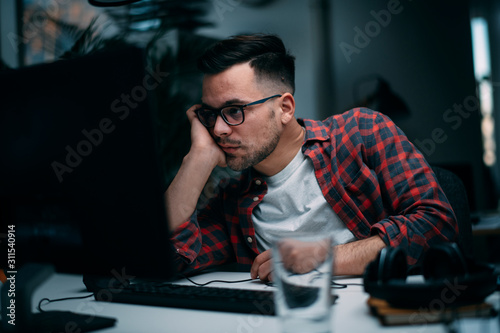 Exhausted businessman in office. Young programmer overworked. 