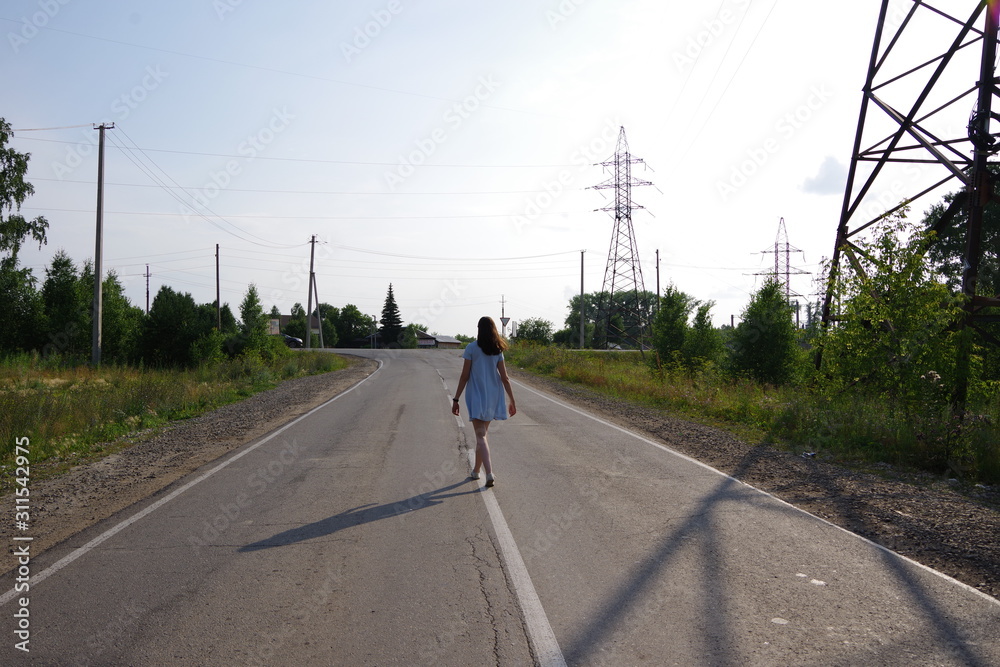 girl in a blue dress runs along the road in the village girl in a blue dress runs along the road in the village