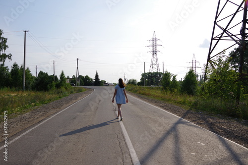  girl in a blue dress runs along the road in the village