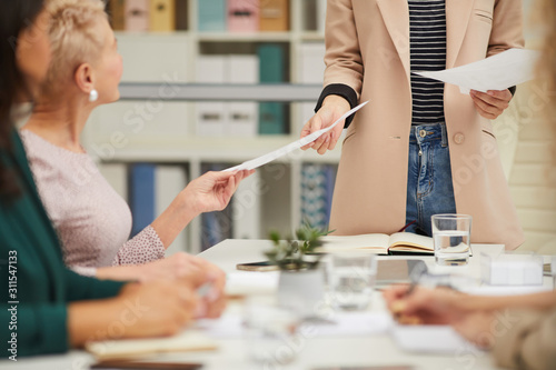 Unrecognizable stylish businesswoman spreading hand-outs at meeting in modern office, horizontal shot photo