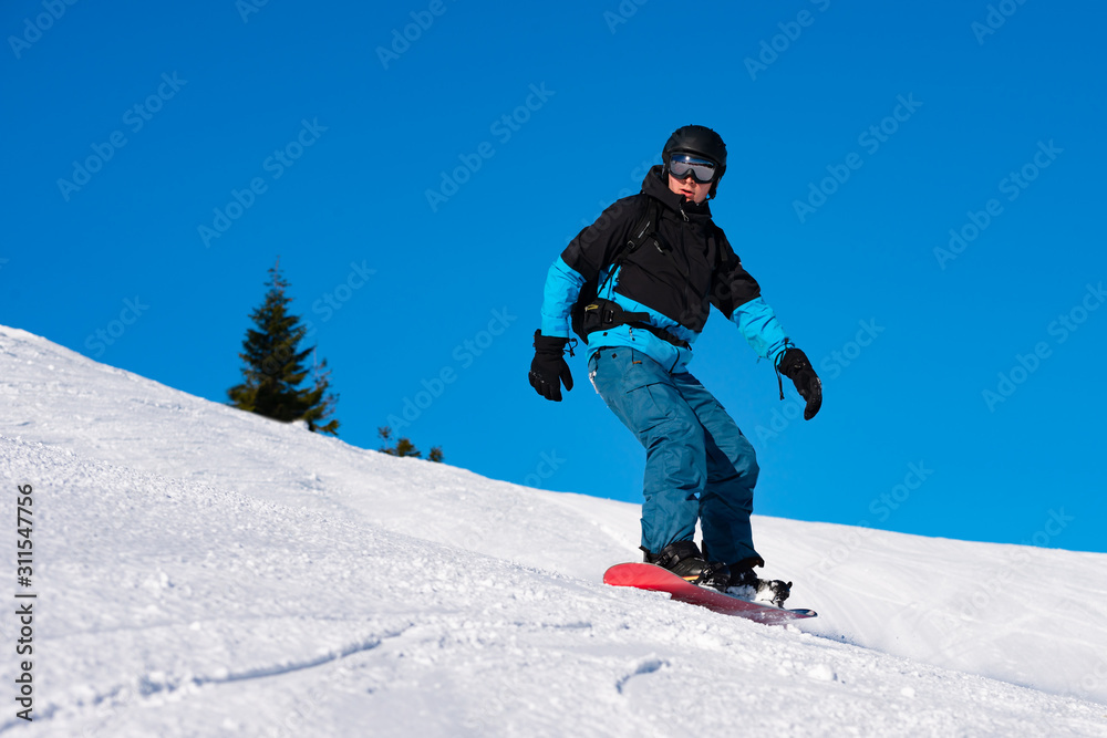 Snowboarder Riding Red Snowboard in Mountains at Sunny Day. Snowboarding and Winter Sports Snowboarder Riding Red Snowboard in Mountains at Sunny Day. Snowboarding and Winter Sports