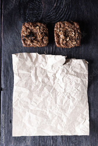 Crumpled kraft paper, oat muffins with chocolate on a wooden table in a rustic style. Culinary business concept