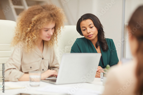 Modern ethnically diverse young women coworking in office medium horizontal shot