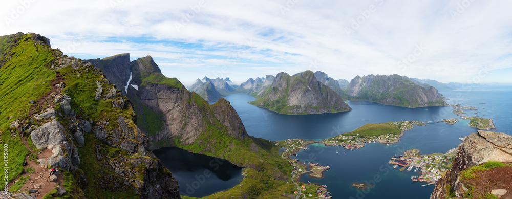 Aerial panoramic view on stunning mountains and village of Reine in Lofoten islands, Norway, from Reinebringen ridge. Scenery view with dramatic mountains and peaks, open sea and sheltered bays.