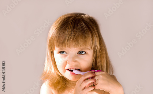Happy baby girl brushing her teeth. Oral hygiene concept. Place to insert text
