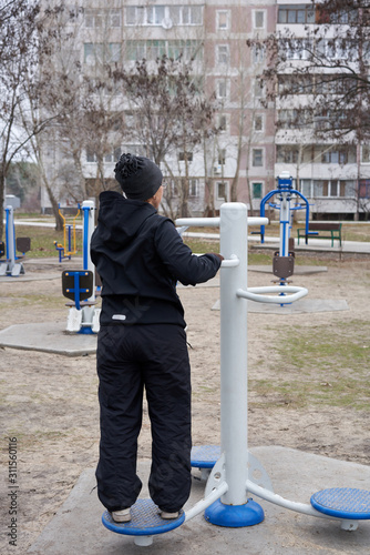 A woman in the early morning is engaged in street simulators. Disc for rotating the waist.