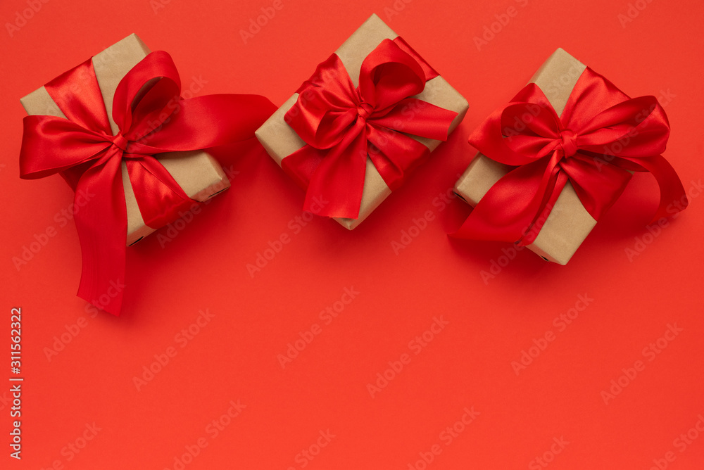 Gift boxes wrapped brown craft paper and red ribbon on red background. Valentines day or Mothers day celebration concept. Top view Gift boxes wrapped brown craft paper and red ribbon on red background. Valentines day or Mothers day celebration concept. Top view