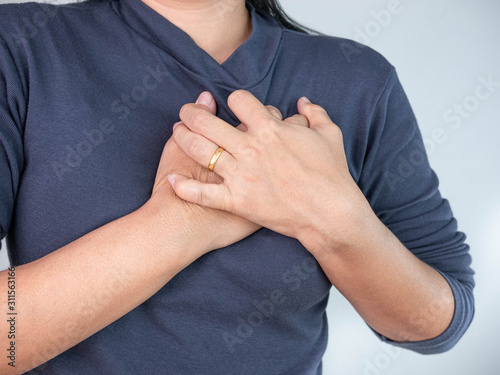 Woman clutching her chest from acute pain and suffering from heart disease. Healthcare and medical concept.