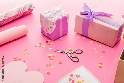 valentines confetti, scissors, wrapping paper, gift boxes on pink background