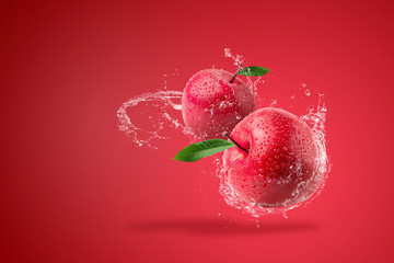 Water splashing on Fresh Red apple on red background.