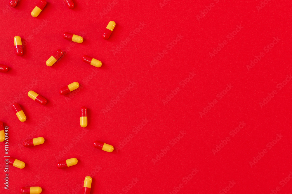 Red-orange pills in capsule on red background, flat lay, top view, copy space Red-orange pills in capsule on red background, flat lay, top view, copy space
