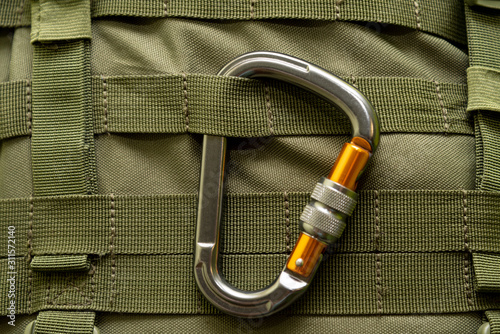 aluminum climbing carabiner attached to a green military tactical backpack