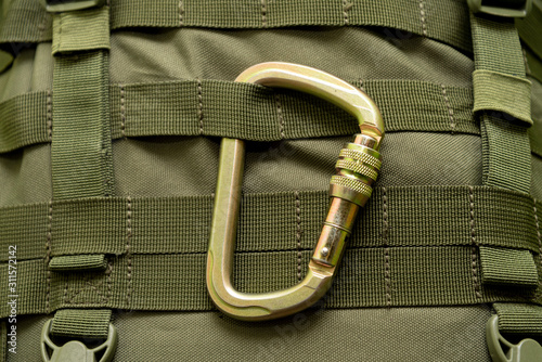 steel climbing carabiner attached to a green military tactical backpack