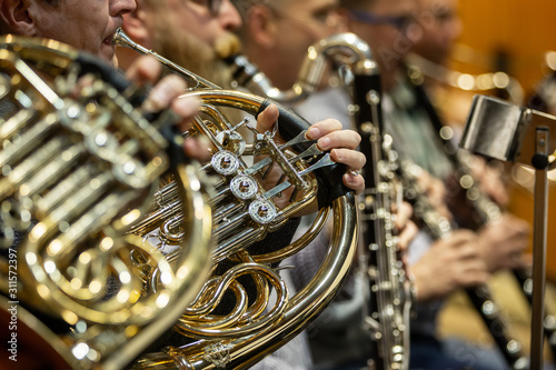 Detail of orchestra, philharmoic player playing on french-horn during huge philharmonic concert (shallow DOF)