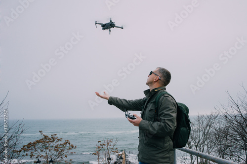  A man driving a drone with a remote control against the backdrop of the sea in foggy weather. Odessa, Ukraine; December 19, 2019: