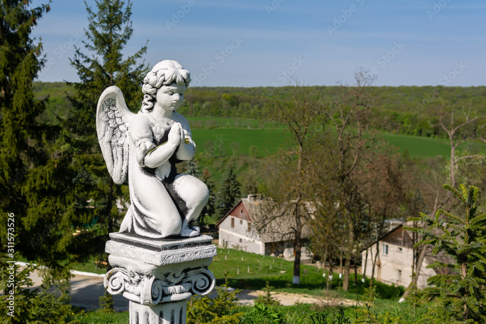 Obraz premium Beautiful old stone statue of praying little Angel