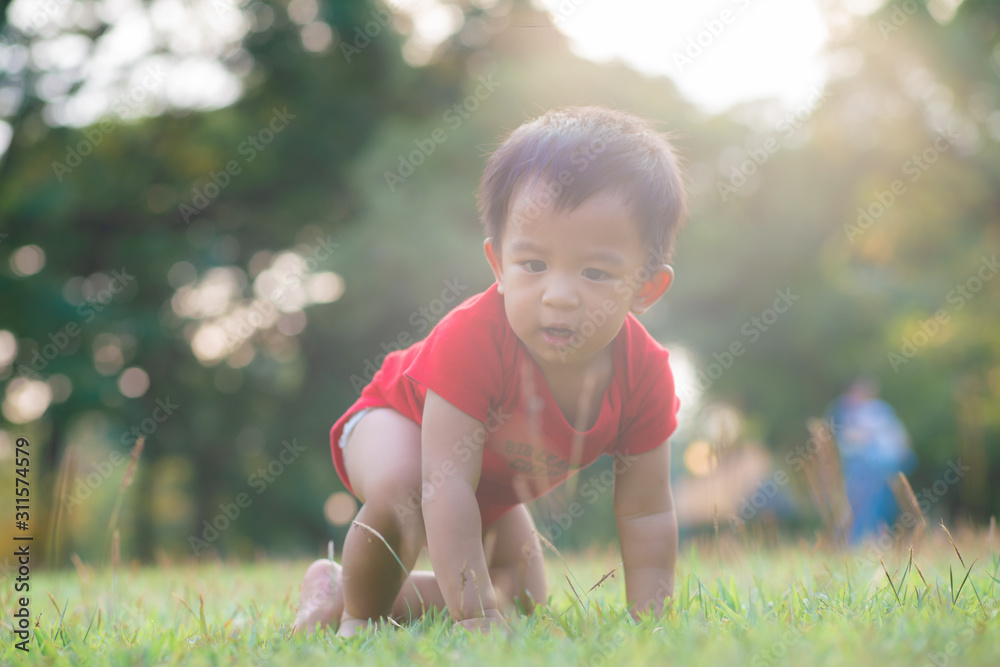 Funny asian boy crawling on green meadow city park sunset Funny asian boy crawling on green meadow city park sunset