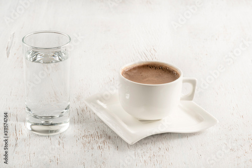 Turkish coffee served with a glass of water on table