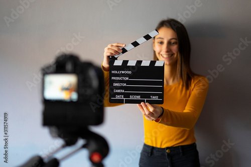 Woman recording a video and holding a movie clapboard.