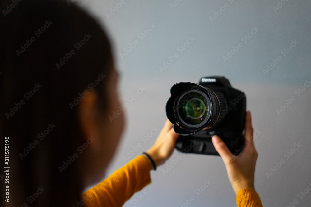 Young woman vlogger dressed in yellow recording a video with her camera.