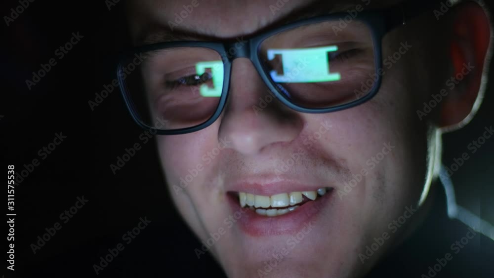 Happy contented businessman reading good news on a tablet late at night. reflection in glasses