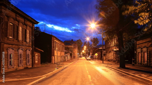 Street with classic wooden houses on both sides of the road at night in Irkutsk  Russia.