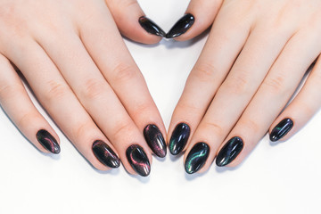 Closeup top view of professional colorful glossy brilliant holiday manicure at fingers of young woman. Modern trendy shiny amazing cat eye effect nail design. Horizontal color photography.