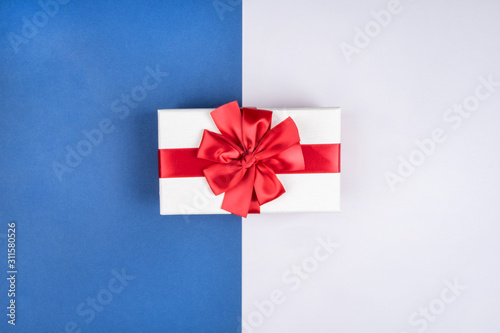 Gift box with red bow on beautiful blue gray background