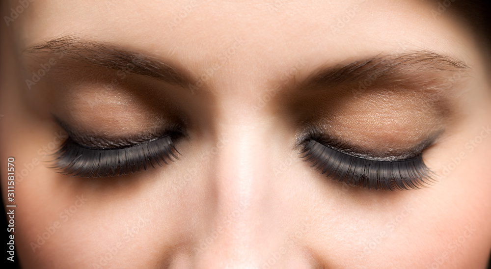 Fototapeta premium Closed eyes of young womans face with extended lashes