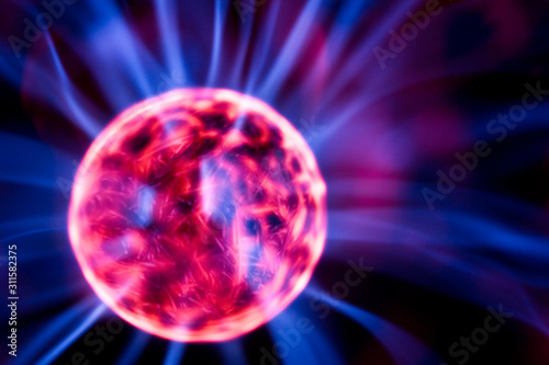 Decoration lamp in shape of plasma ball with red and blue electrodes  close-up