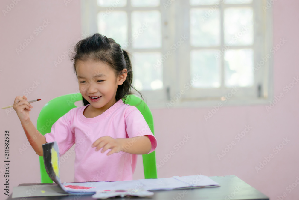An Asian kindergarten girl is coloring on the table. An Asian kindergarten girl is coloring on the table.