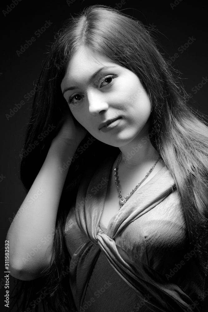 Black and white portrait of woman in cocktail dress standing over dark background