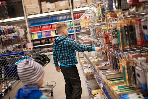 Little boy in the store at the shelves with stationery