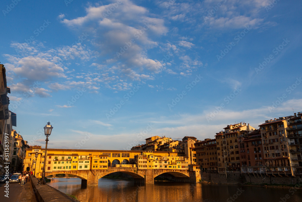 The Ponte Vecchio, a medieval stone closed-spandrel segmental arch bridge over the Arno River, in Florence, Italy, noted for still having shops built along it.  