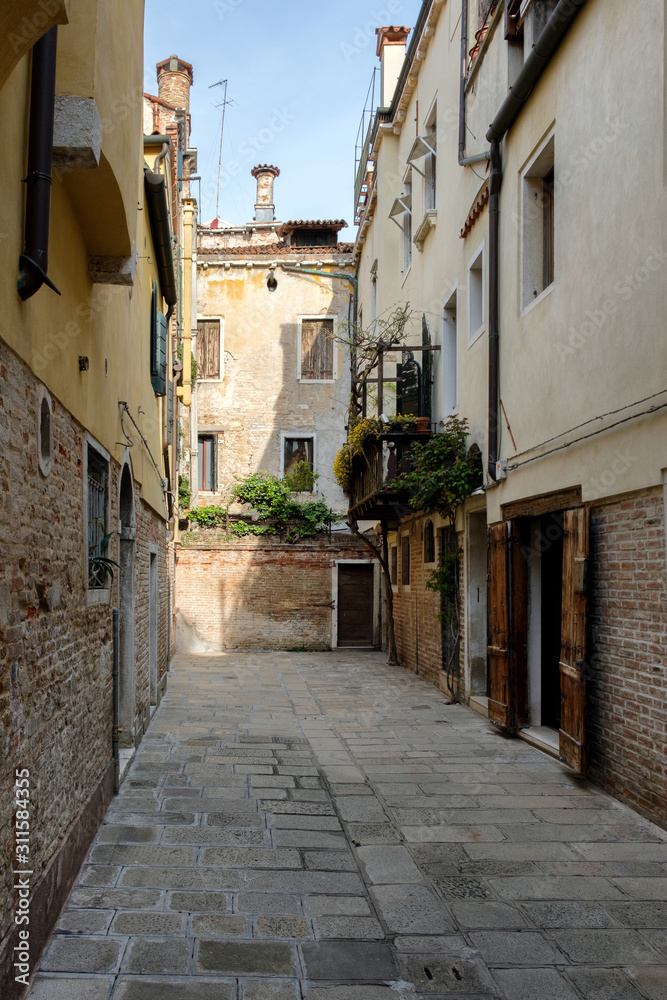 Narrow stone courtyard between the buildings. Sunny day, Venice, Italy.