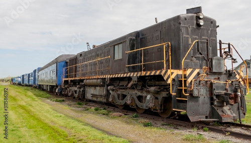 Old diesel locomotive with trains cars in a field.