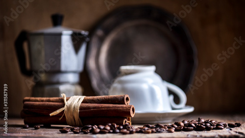 Fotografie Cup of black coffee, coffee pot and cinnamon flavor on vintage wooden table