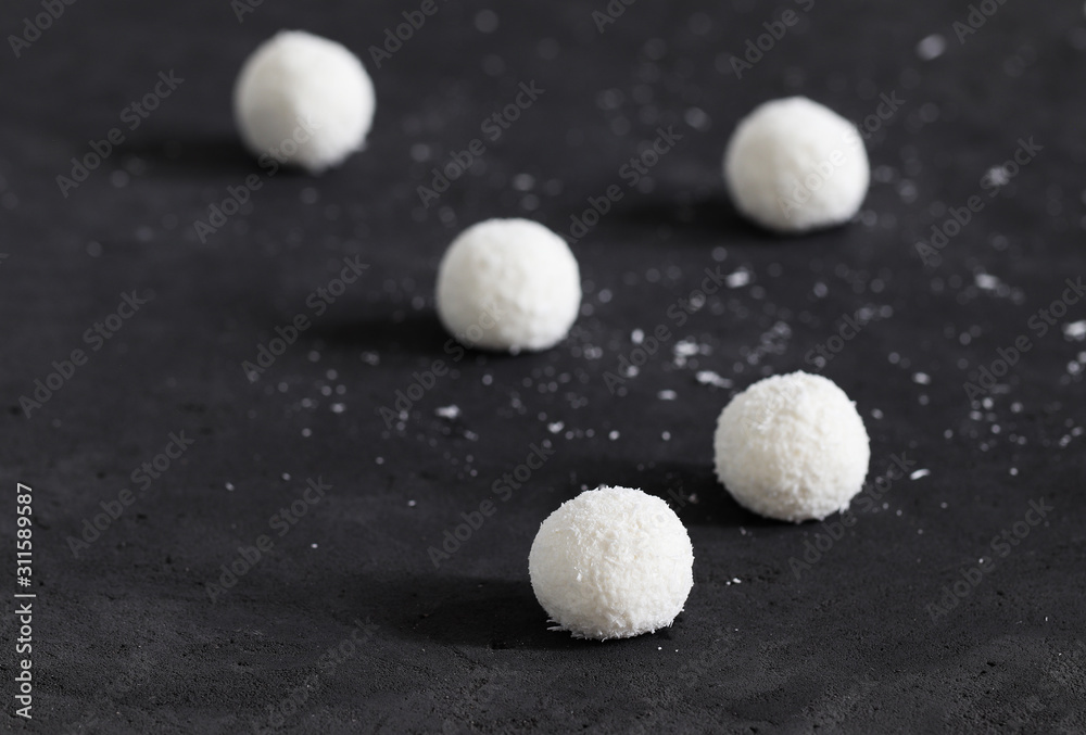 Dessert curd balls in coconut shavings on a dark gray background Dessert curd balls in coconut shavings on a dark gray background