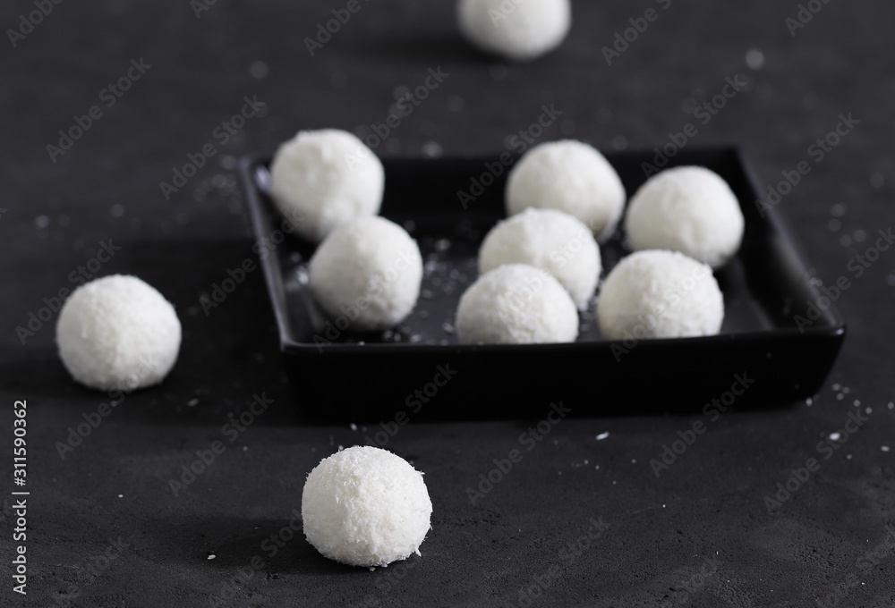 Dessert curd balls in coconut shavings on a dark gray background Dessert curd balls in coconut shavings on a dark gray background