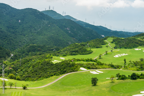 A green golf field in the valley and mountains background at Shenzhen Overseas Chinese Town East (OCT East) in Guangdong, China. A resort with themed parks: Knight Valley, Tea Stream and Wind Valley.
