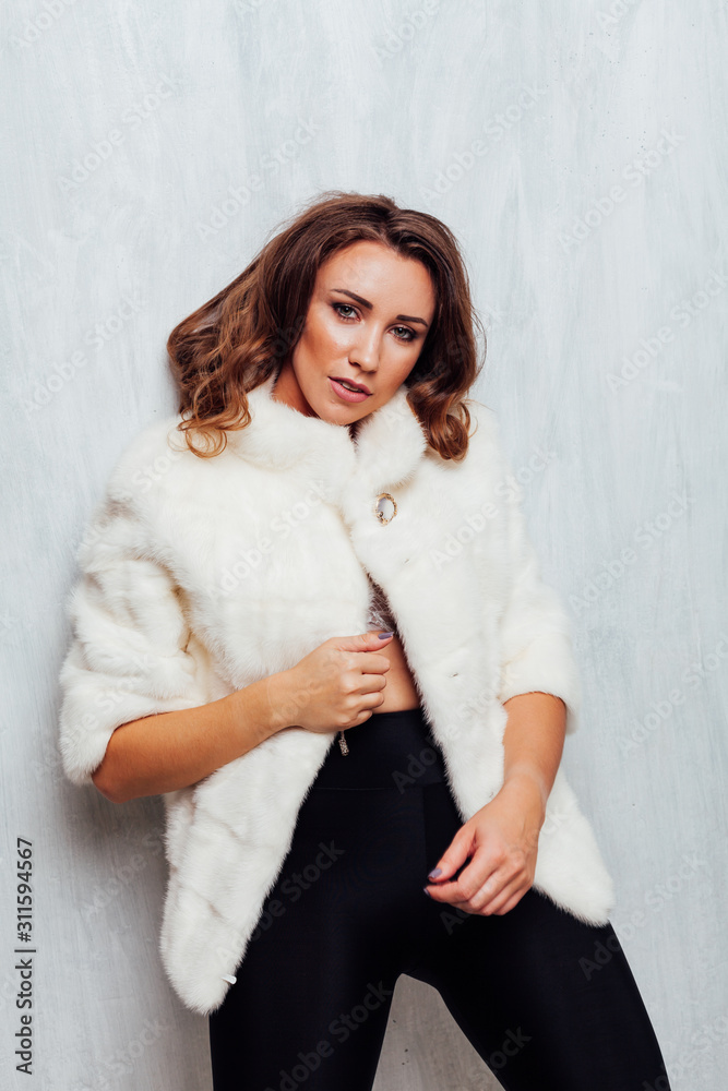 portrait of a beautiful fashionable woman with hair curls in a white fur coat in winter