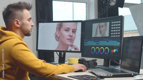 Freelance videographer colorist editing footage using professional software, monitor and montage console.