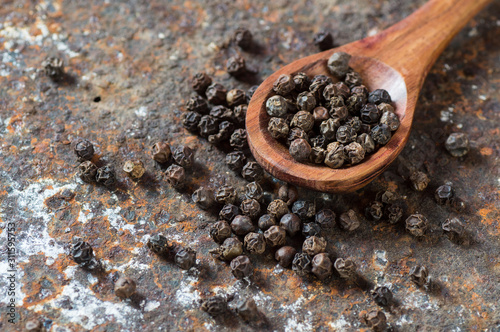 Peppercorns in wooden spoon on texture background