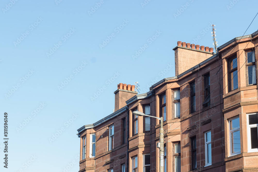 Fototapeta premium Glasgow street photography: brick buildings against the blue sky
