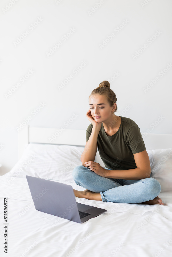 Pretty young woman using her laptop in bed Pretty young woman using her laptop in bed