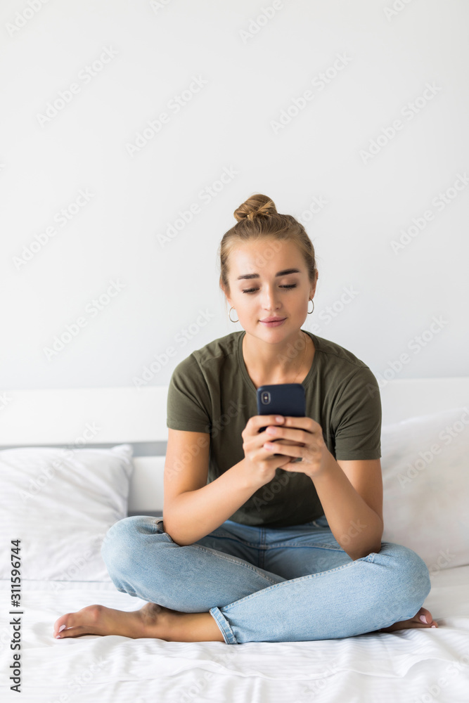 Relaxed young woman at home reading a text message in her bed Relaxed young woman at home reading a text message in her bed