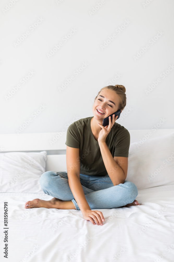 Smiling woman talking via telephone and laying on the bed. Smiling woman talking via telephone and laying on the bed.