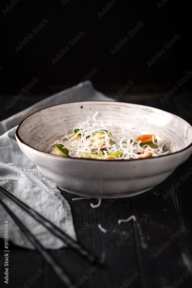 Asian beef salad with cucumber, noodles and rice flakes. Thai dish on black wooden background. Asian beef salad with cucumber, noodles and rice flakes. Thai dish on black wooden background.