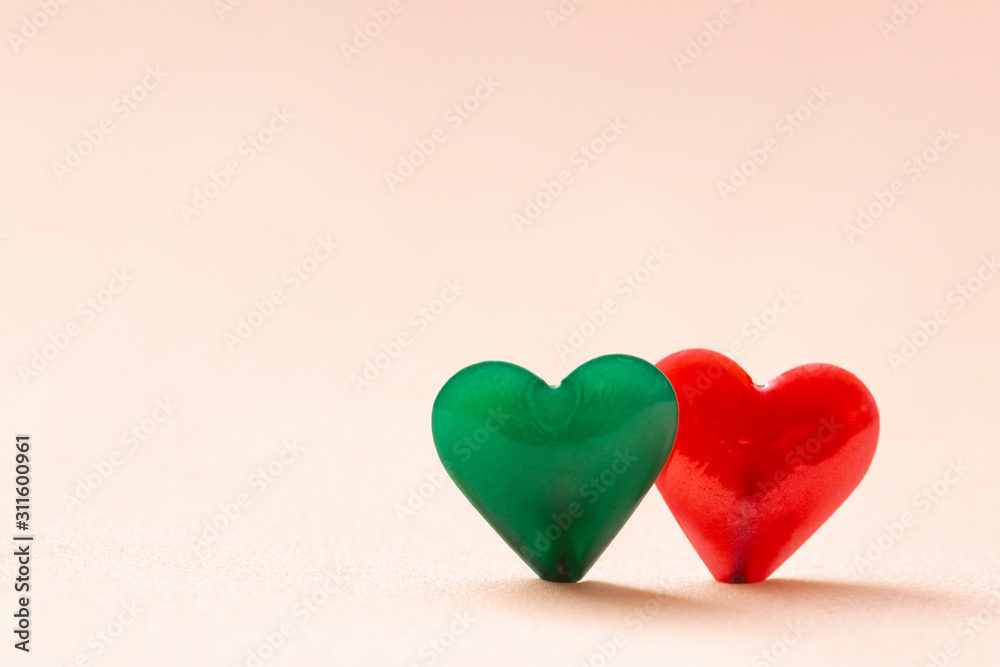 Two green and red hearts on a clear and clean pink background. Concept of love and company. Valentine's day